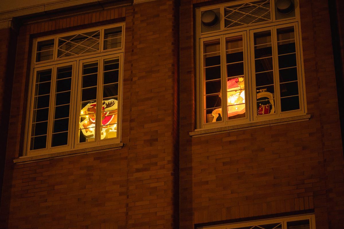 写真：イルミネーション（2）中庭から見上げる様に本館の一つの教室の窓を撮影している。窓にはサンタクロースとトナカイが光って見える。