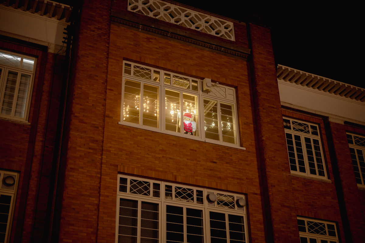 窓辺に飾られたサンタクロースを、屋外から撮影した写真。