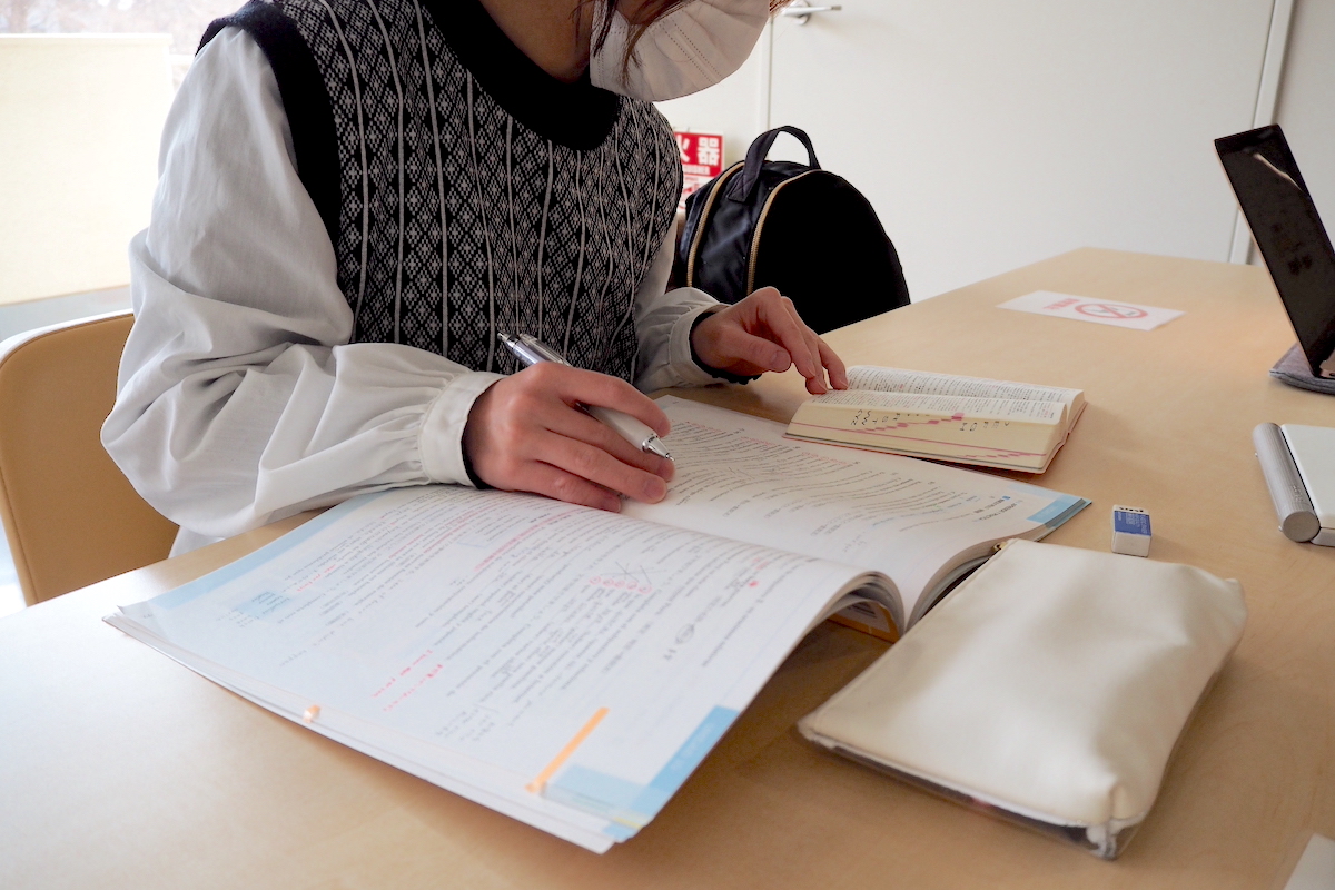 机に向かって勉強をする学生の写真。左手側に辞書を開き、辞書を見ながら第二外国語であるスペイン語を勉強中。